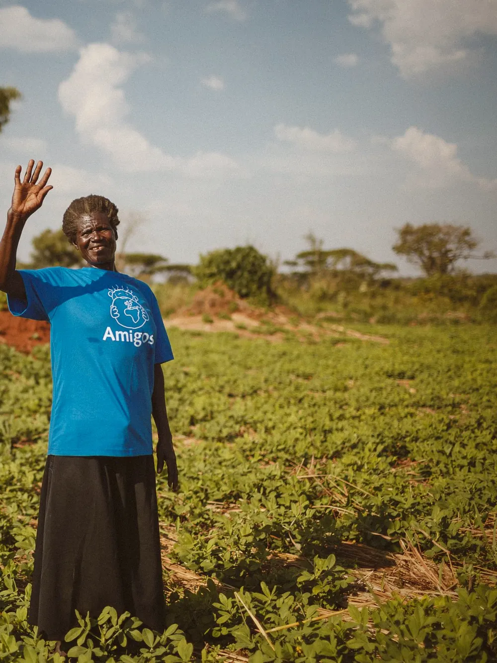 A farmer waving from her green field