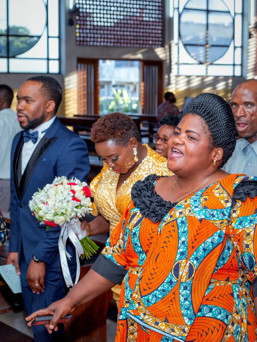 Members of a congregation in bright dress at a wedding service