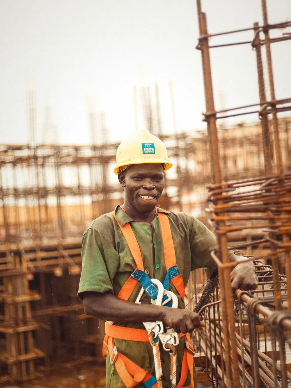 A builder in a hard hat smiling on a rebar site