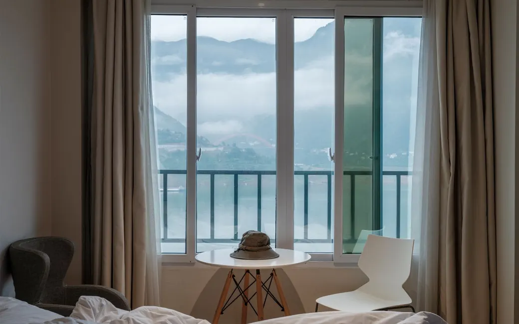 A quiet room with a wide window over misty hills