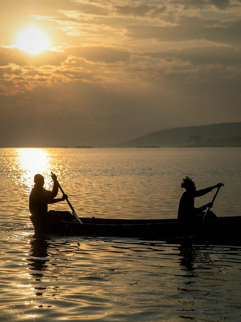 Fishermen paddling a canoe across the lake at sunset