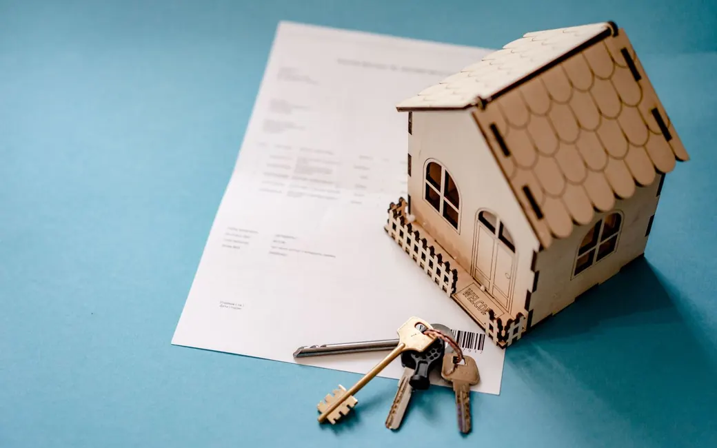 A signed contract with a set of house keys and a model house