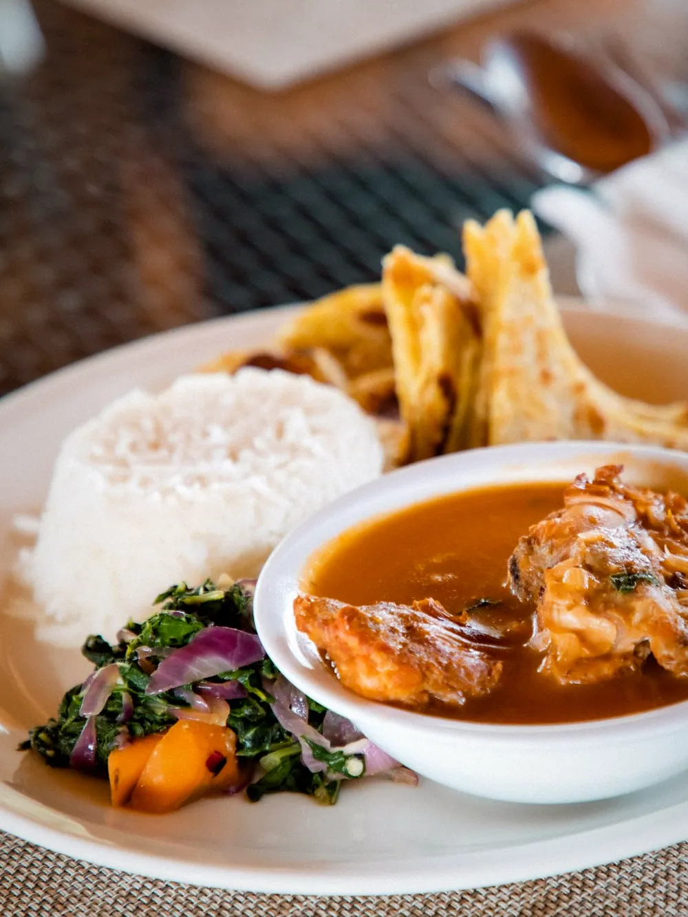 A plate of rice, chapati and stew with a fresh juice