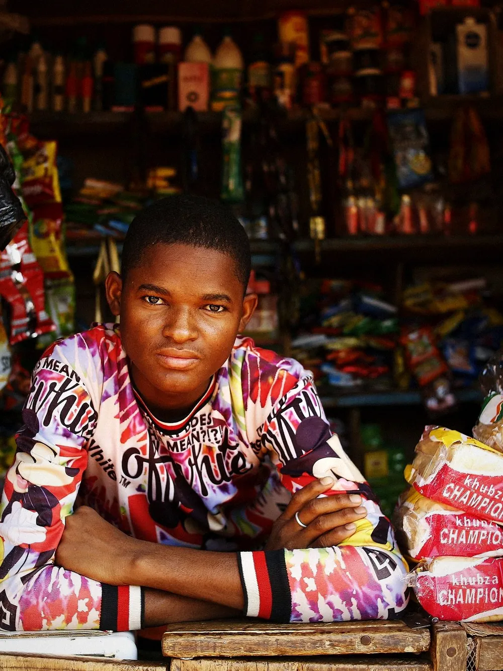 A shopkeeper leaning on the counter of his stocked kiosk