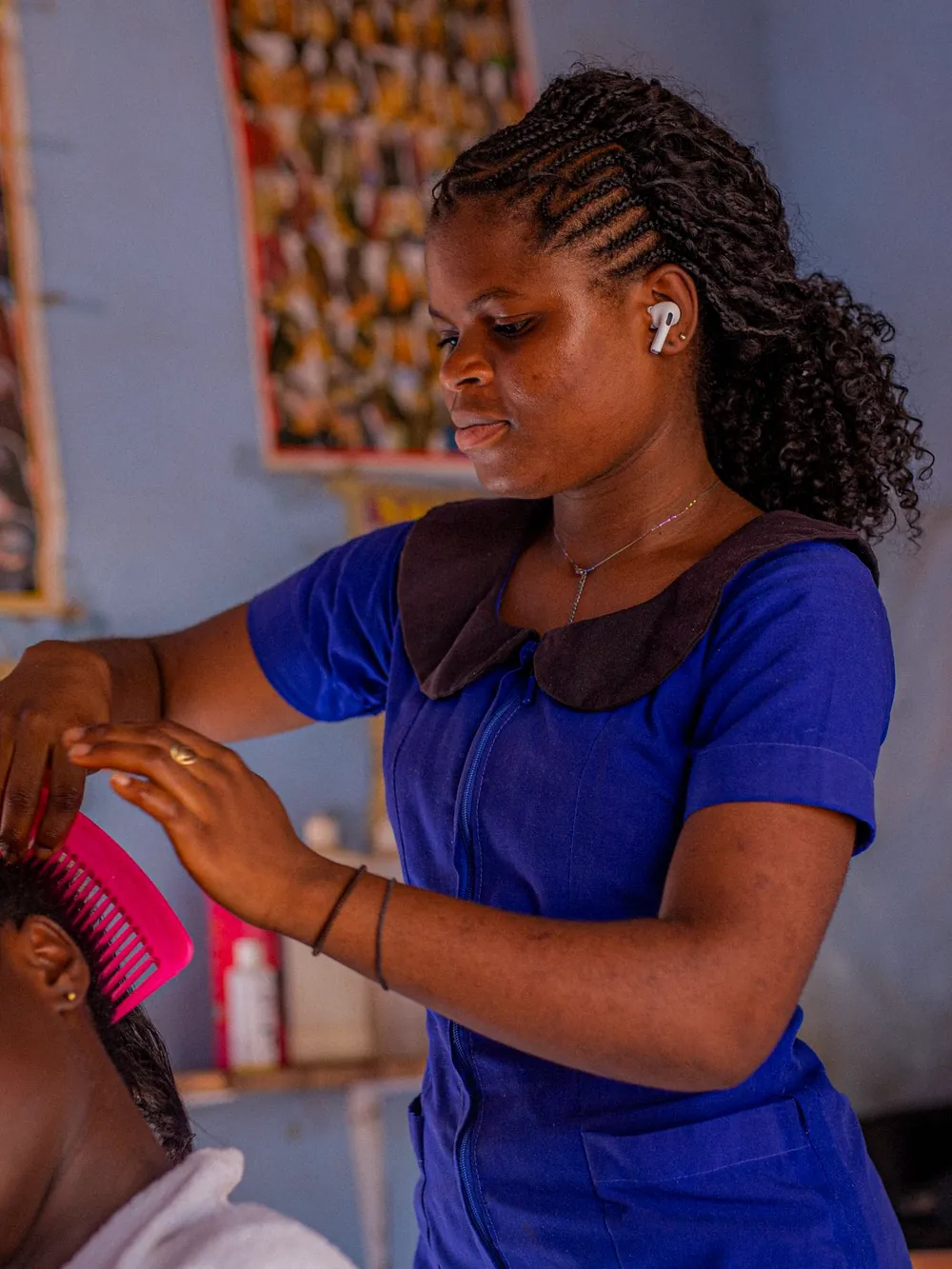 A hairdresser braiding a client's hair in a salon