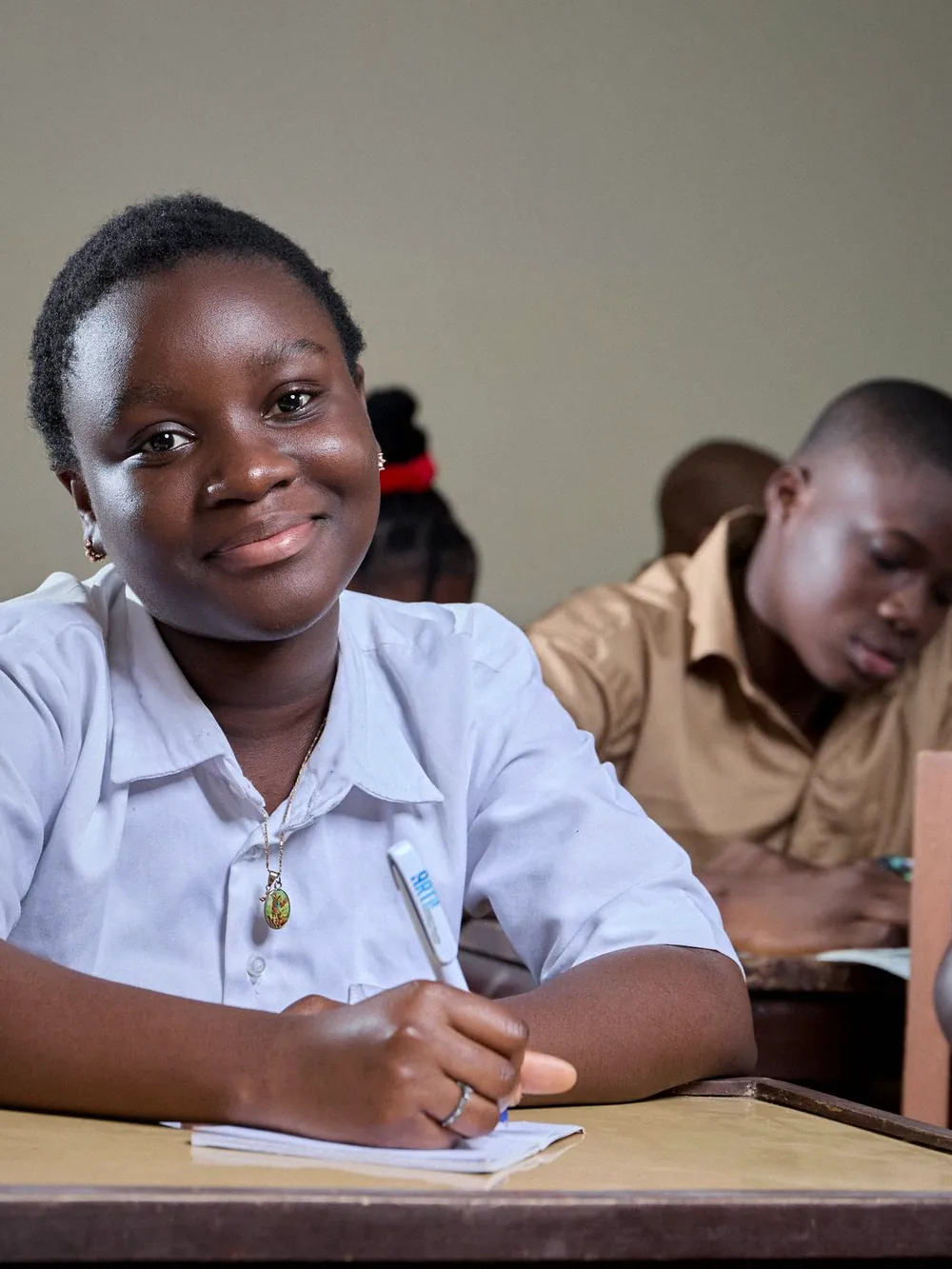 A smiling pupil at her desk in a classroom